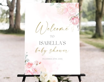 May include: A welcome sign for Isabella's baby shower, featuring elegant gold script and floral accents. The sign includes the date, December 20th, 20XX, and is decorated with pink and gold flowers. The sign is displayed on a black easel.