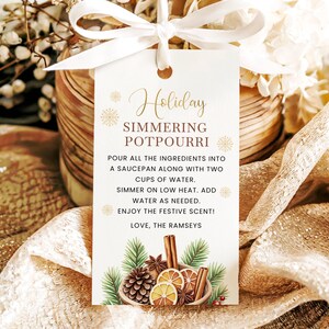 May include: A rectangular white gift tag with a white ribbon, featuring the text Holiday SIMMERING POTPOURRI, instructions for use, and the signature Love, The Ramseys. The bottom displays a watercolor illustration of pine, cinnamon, and citrus.