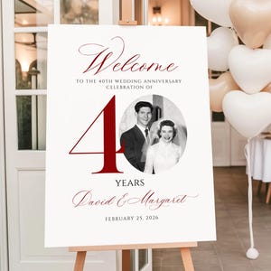 May include: A white rectangular welcome sign for a 40th wedding anniversary celebration. It features the text Welcome to the 40th wedding anniversary celebration of, a large red number 40, a black and white photo of a couple, and the names David & Margaret.
