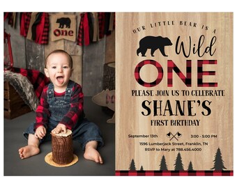 以下が含まれることがあります： 森をテーマにした男の子の1歳の誕生日パーティーの招待状。招待状には、黒いクマと「Our little bear is a Wild One」という文字が書かれています。招待状には、赤と黒のチェック柄と「Please join us to celebrate Shane's First Birthday」という文字も書かれています。招待状には、パーティーの日時と場所が記載されています。