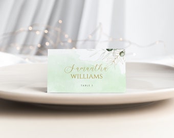 May include: Green and white watercolor place card with gold lettering. The card reads "Samantha Williams, Table 1".