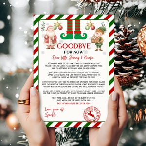 Peut inclure: Une lettre sur le thème de Noël, tenue par une personne, avec un design festif à rayures rouges et vertes. La lettre comprend des illustrations du Père Noël et d'un elfe, avec le texte "Goodbye For Now" et un message à "Johnny & Amelia."