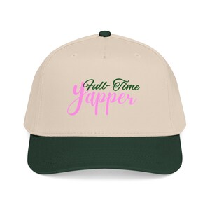 May include: A beige baseball cap with a dark green brim and button. The cap features the text "Full Time Yapper" in pink and green script. The hat is a classic six-panel design.