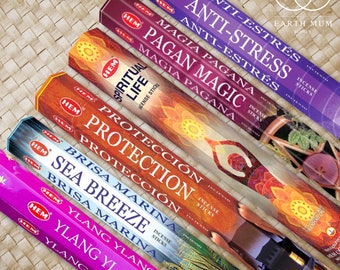 May include: A set of six incense sticks with colorful packaging. The packaging features images of flowers, hands, and a wheel. The incense sticks are labeled with the following scents: Anti-Stress, Pagan Magic, Spiritual Life, Protection, Sea Breeze, and Ylang Ylang.