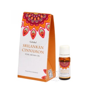 May include: A box and a small bottle of Goloka Sri Lankan Cinnamon Pure Aroma Oil. The box is orange and white with a decorative mandala design in red, orange, and yellow. The bottle has a white cap and is filled with amber liquid.