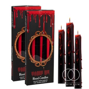 May include: Black taper candles with red wax dripping, alongside two boxes of candles. The boxes feature a black background with red wax drips and gold ornate frames. The text on the boxes reads "Vamp Re Blood Candles".