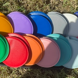 May include: Assortment of 14 round, colorful, fabric-covered coin purses. The purses are arranged in a semi-circle, with the colors ranging from yellow, green, red, orange, pink, blue, and purple.