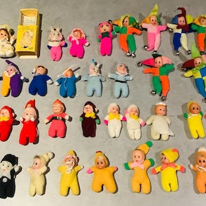 Puede incluir: Una colección de 30 pequeñas muñecas de fieltro de colores. Las muñecas están vestidas con diferentes atuendos, incluidos trajes de payaso, vestidos y pantalones. Algunas muñecas tienen cascabeles en los zapatos.