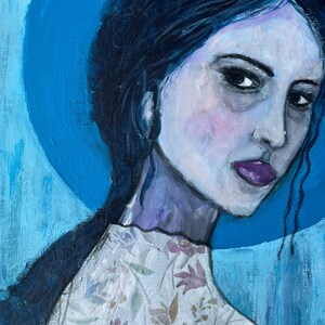Puede incluir: Pintura original de una mujer con cabello oscuro y labios morados. Lleva una blusa blanca con un estampado floral. El fondo es azul brillante con un círculo azul más oscuro detrás de su cabeza.
