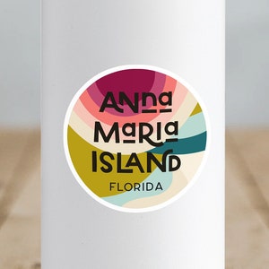 May include: White water bottle with a round sticker featuring a colorful abstract design and the text "Anna Maria Island, Florida".