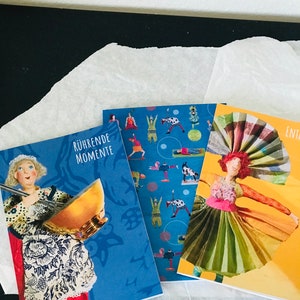 Könnte beinhalten: Drei Grußkarten mit bunten Illustrationen und Text. Die erste Karte ist blau mit einer Frau, die eine Rührschüssel und einen Schneebesen hält. Der Text lautet "Rührende Momente". Die zweite Karte ist blau mit einem Muster von Menschen, die Yoga-Posen machen. Die dritte Karte ist gelb mit einer Frau in einem bunten Kleid. Der Text lautet "Ent".