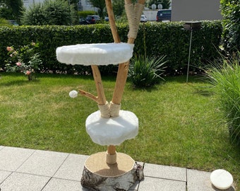 May include: A wooden cat tree with three platforms covered in white faux fur. The tree is wrapped in natural rope and has a birch bark base.