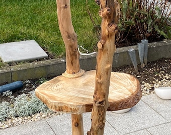 Peut inclure: Un stand en bois avec trois étagères faites de branches d'arbres et de tranches de troncs d'arbres. Le stand est en bois naturel et a un aspect rustique.