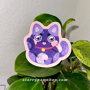 May include: A sticker featuring a purple cat with large eyes, a red collar, and a gold bell. The cat is in a waving pose, with a pink outline. The sticker is placed on a green plant.
