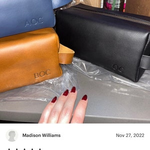 May include: Three leather travel bags in blue, brown, and black with the initials "AOC" and "BOC" embossed on the front.