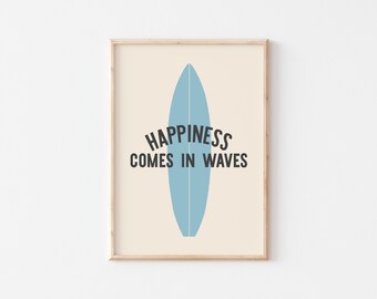 May include: A framed print featuring a light blue surfboard illustration on a cream background. The text "HAPPINESS COMES IN WAVES" is printed in black above the surfboard. The print has a wooden frame.