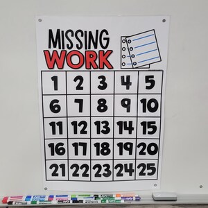 May include: A white board with a printed "MISSING WORK" chart. The chart has a grid with numbers 1-25. A notepad graphic is in the upper right corner. Below the board are colorful markers and an eraser.