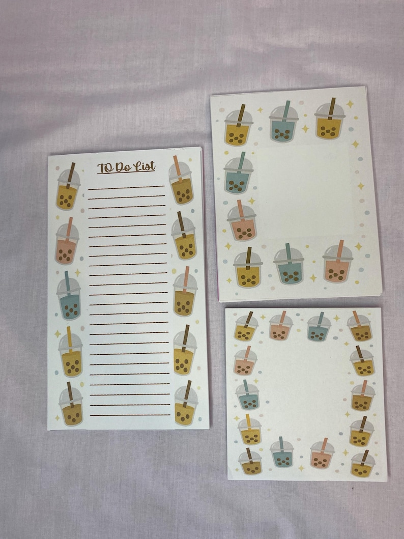 May include: Three white notepads with a bubble tea theme. One notepad is a to-do list with lines and bubble tea illustrations. The other two notepads have bubble tea illustrations around the edges. The bubble tea illustrations are in shades of brown, pink, blue, and yellow.