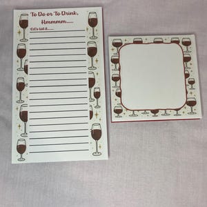 May include: A white notepad and a square memo pad with a wine theme. The notepad has lines for writing and the text "To Do or To Drink, Hmmmm..." and "Let's list it..." The memo pad has a blank space.