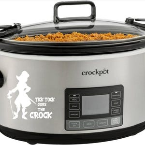 May include: A stainless steel Crock-Pot slow cooker with a clear glass lid. The cooker has a black handle and a digital display. A white graphic of a pirate with the text "Tick Tock Goes The Crock" is on the front.