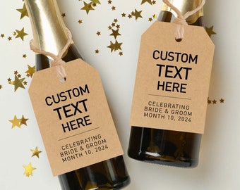 May include: Two small champagne bottles with brown paper tags tied around the necks. The tags have black text that reads "CUSTOM TEXT HERE" and "CELEBRATING BRIDE & GROOM MONTH 10, 2024". The bottles are surrounded by gold star confetti on a white background.