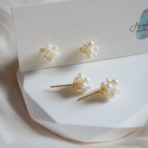 May include: A pair of pearl earrings with gold posts. The pearls are clustered together in a small, irregular shape.