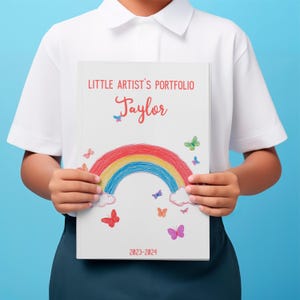 Custom art album featuring toddler drawings and childhood creativity. Close-up of personalized cover with child’s name and date on art keepsake book.