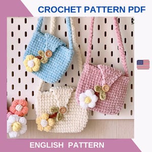 Puede incluir: Tres bolsos de ganchillo en azul claro, rosa y crema, cada uno adornado con una flor y un botón de madera. Los bolsos tienen correas largas y se muestran contra una pared perforada blanca. El texto "CROCHET PATTERN PDF" y "ENGLISH PATTERN" son visibles.