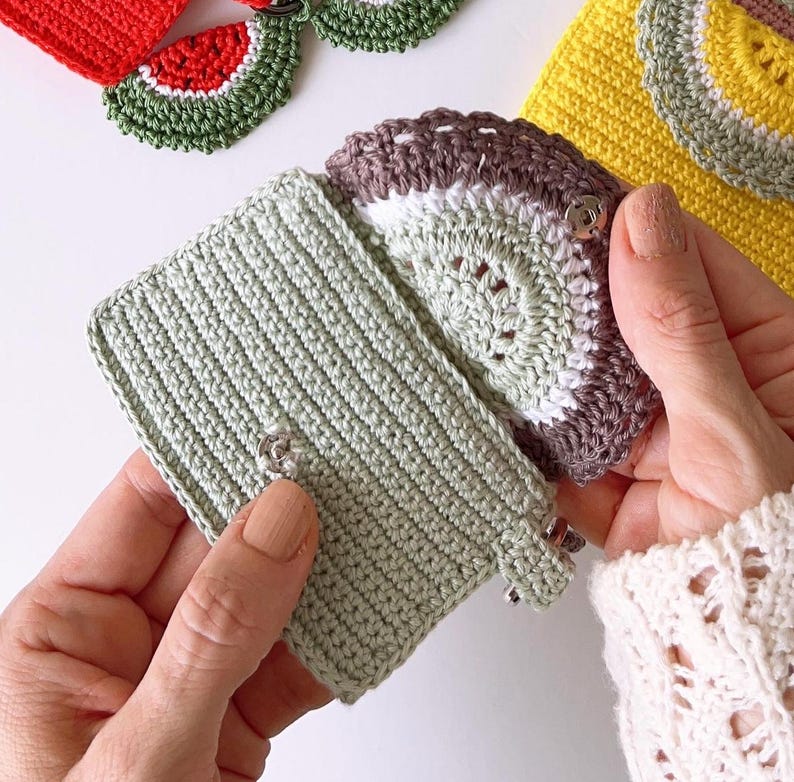 Puede incluir: Un conjunto de monederos de ganchillo en varios colores y patrones, incluyendo verde, amarillo, blanco y marr&oacute;n. Los monederos est&aacute;n decorados con dise&ntilde;os de frutas de ganchillo, como sand&iacute;a y kiwi. Los monederos tienen un cierre de presi&oacute;n.