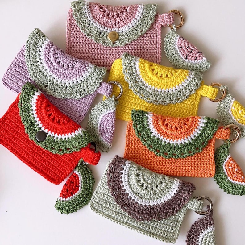 Puede incluir: Seis monederos de ganchillo con forma de sand&iacute;a en una variedad de colores, incluyendo rosa, morado, amarillo, naranja y verde. Cada monedero tiene un peque&ntilde;o amuleto de sand&iacute;a de ganchillo.