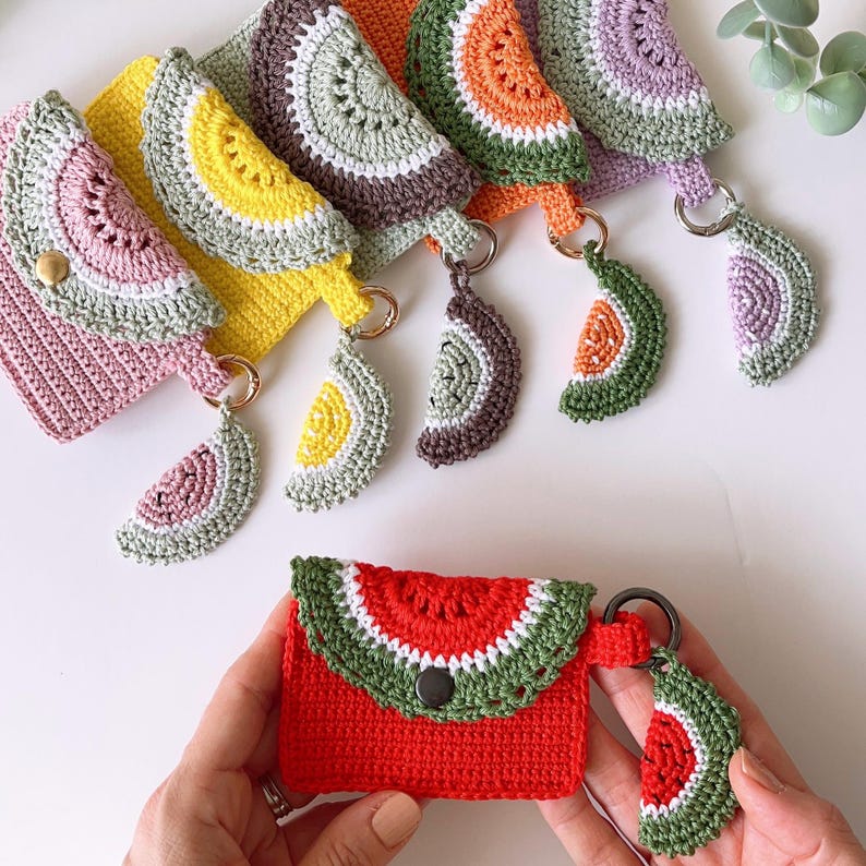 Puede incluir: Un conjunto de seis monederos de ganchillo con forma de sand&iacute;a con llaveros a juego. Los monederos son de varios colores, incluyendo rosa, amarillo, verde, naranja y morado. Cada monedero tiene un llavero de ganchillo con forma de rodaja de sand&iacute;a.