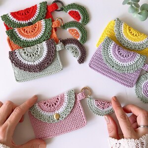 Puede incluir: Cinco monederos de ganchillo con forma de sand&iacute;a con llaveros a juego. Cada monedero tiene un esquema de color diferente, incluyendo rojo, naranja, verde, morado y rosa.
