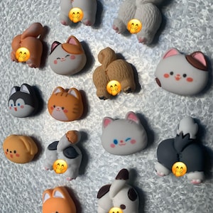 May include: A collection of 15 colorful, cartoon animal-shaped magnets. The magnets feature various animals, including cats, dogs, foxes, and squirrels. Each magnet has a unique expression and is made of a soft, squishy material.
