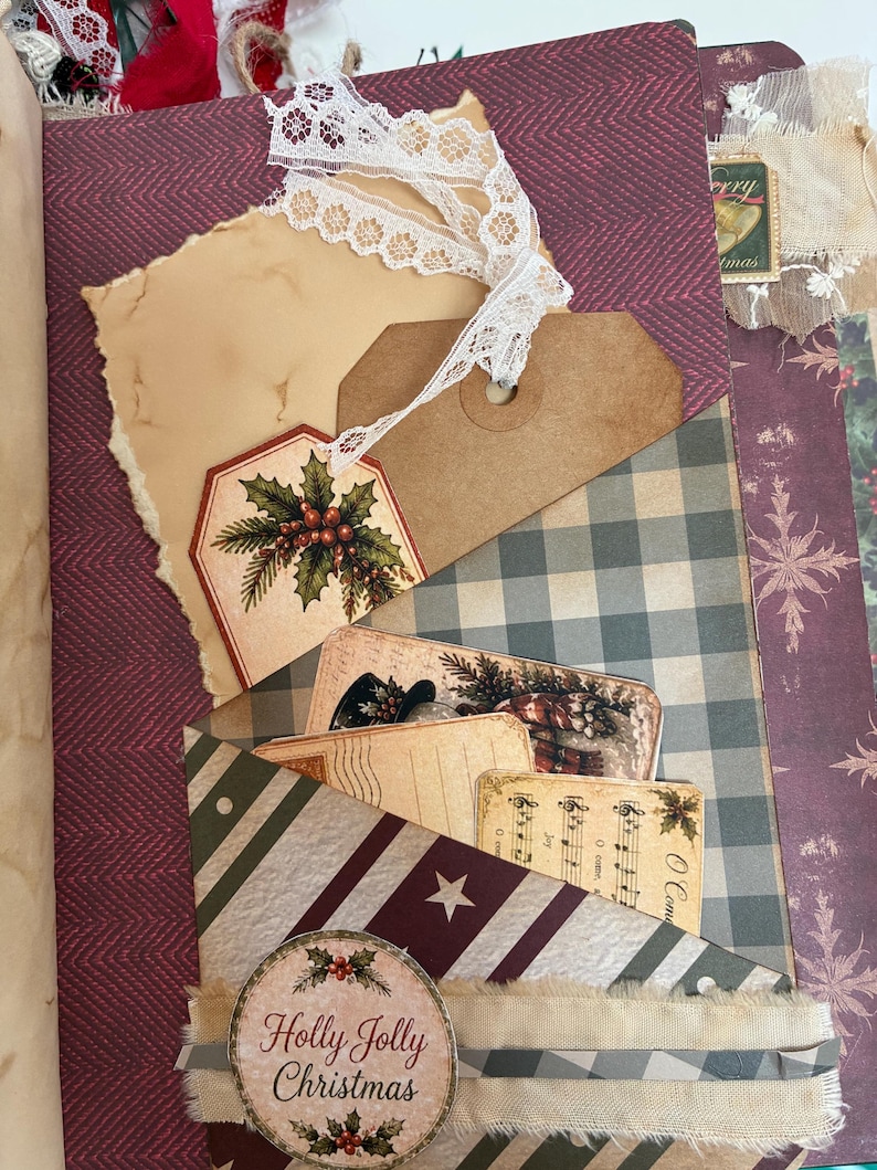 May include: A scrapbook page featuring a pocket with a burgundy herringbone background, a white lace ribbon, a brown paper tag with a holly illustration, and several vintage-style cards including one with the text Holly Jolly Christmas.