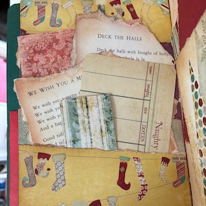 May include: A scrapbook page featuring a yellow background with a pattern of hanging Christmas stockings and the text HO HO. It includes torn paper inserts with the lyrics to Deck the Halls and We Wish You a Merry Christmas, plus a Naughty list card.