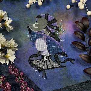 May include: Cross-stitch design of a celestial figure with a crescent moon and stars. The figure is depicted in shades of purple, blue, and white, with a black outline. The background is a gradient of blues and greens, with floral accents.