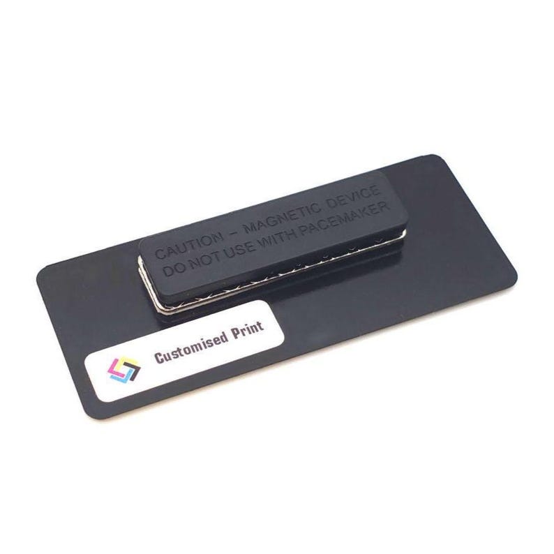May include: A black name tag with a magnetic backing. The tag has the text "CAUTION - MAGNETIC DEVICE DO NOT USE WITH PACEMAKER" and a white sticker that says "Customised Print" with a colorful logo.