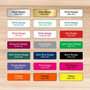May include: A collection of rectangular name badges in various colours including silver, gold, white, red, burgundy, grey, light green, dark green, dark blue, black, purple, pink, orange, and yellow, each featuring printed text describing its colour.