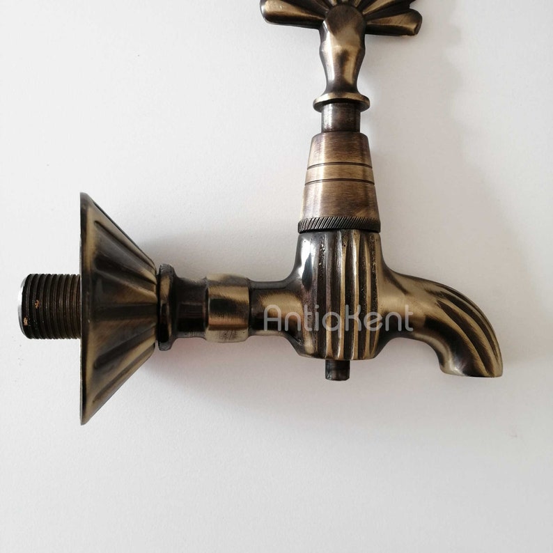 May include: Antique brass faucet with a decorative fan-shaped spout and a ribbed design. The faucet has a threaded connection on the back.