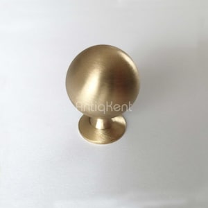 Op de afbeelding: Een ronde kastknop van geborsteld goud met een ronde basis.