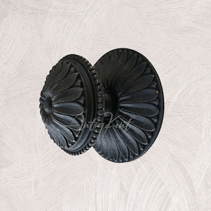 Pode incluir: Maçaneta de porta de metal preto com um design floral decorativo. A maçaneta é redonda e tem um centro elevado.