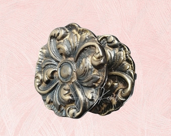 May include: Two ornate gold-toned metal drawer pulls with a floral design.