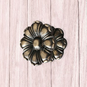 Könnte beinhalten: Zwei verzierte, goldfarbene, blumenförmige Schubladenknöpfe aus Metall.