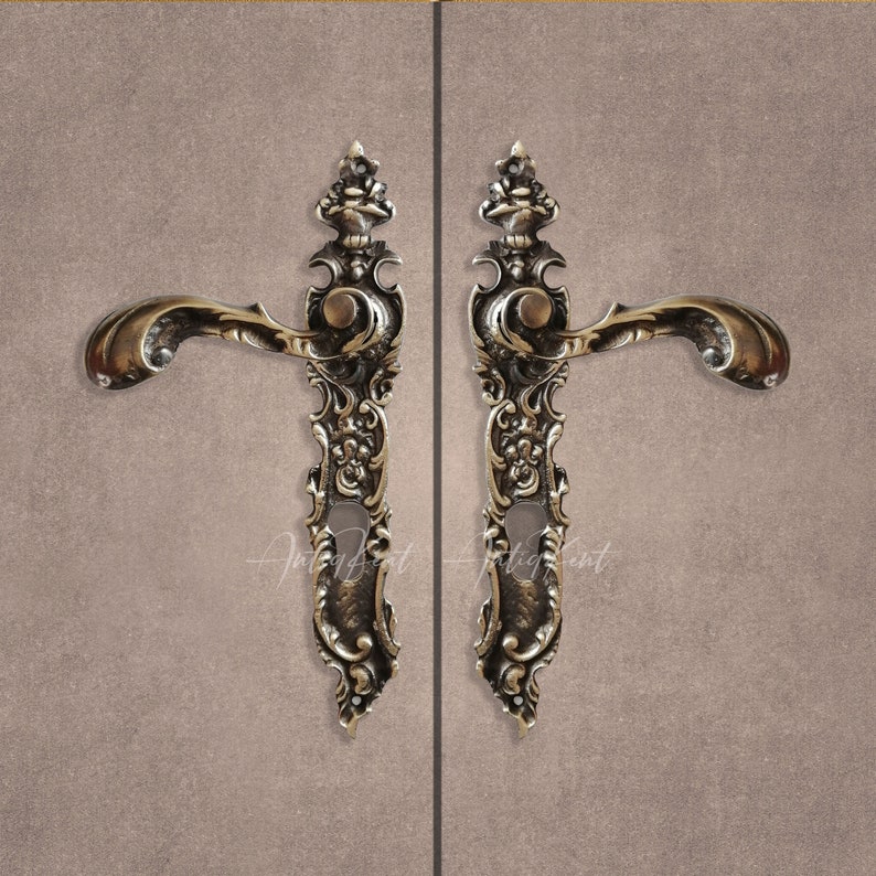 May include: A pair of ornate, antique-style door handles with intricate floral designs. The handles are made of brass and have a polished finish.