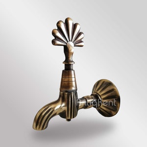 May include: Antique brass faucet with a decorative fan-shaped spout and a wall mount. The faucet has a vintage design and a distressed finish.