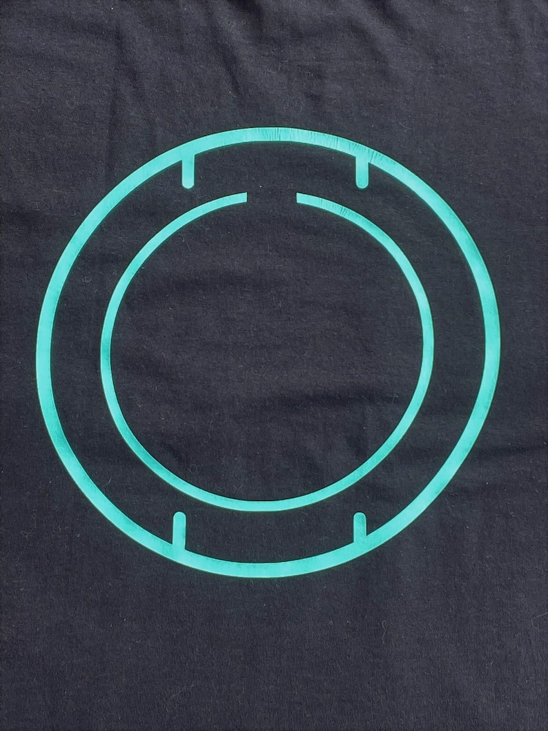 May include: A teal blue circle with a smaller teal blue circle inside, both with four small lines on the outer edge.