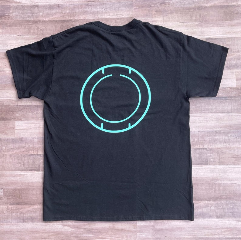 May include: Black t-shirt with a teal blue circle design on the back.