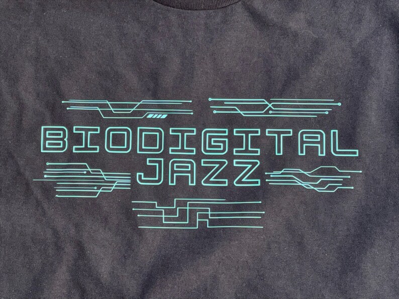 May include: Black t-shirt with a teal blue graphic design that says "Biodigital Jazz" with stylised circuit board lines.