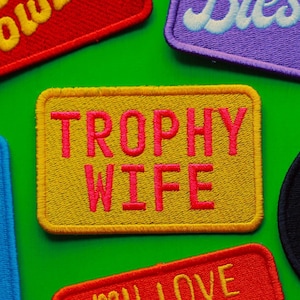 Peut inclure: Assortiment de patchs brodés colorés avec différentes phrases, dont "trophy wife", "blessed", "wee cowboy", "in my happy girl era" et "birth boy".