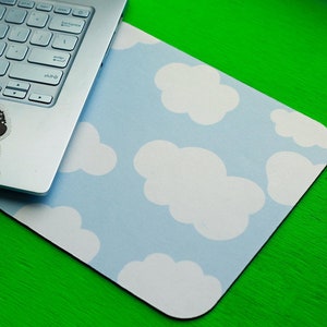 May include: A blue and white cloud-patterned mousepad with a sticker of a person sitting in a meditative pose on a silver laptop.